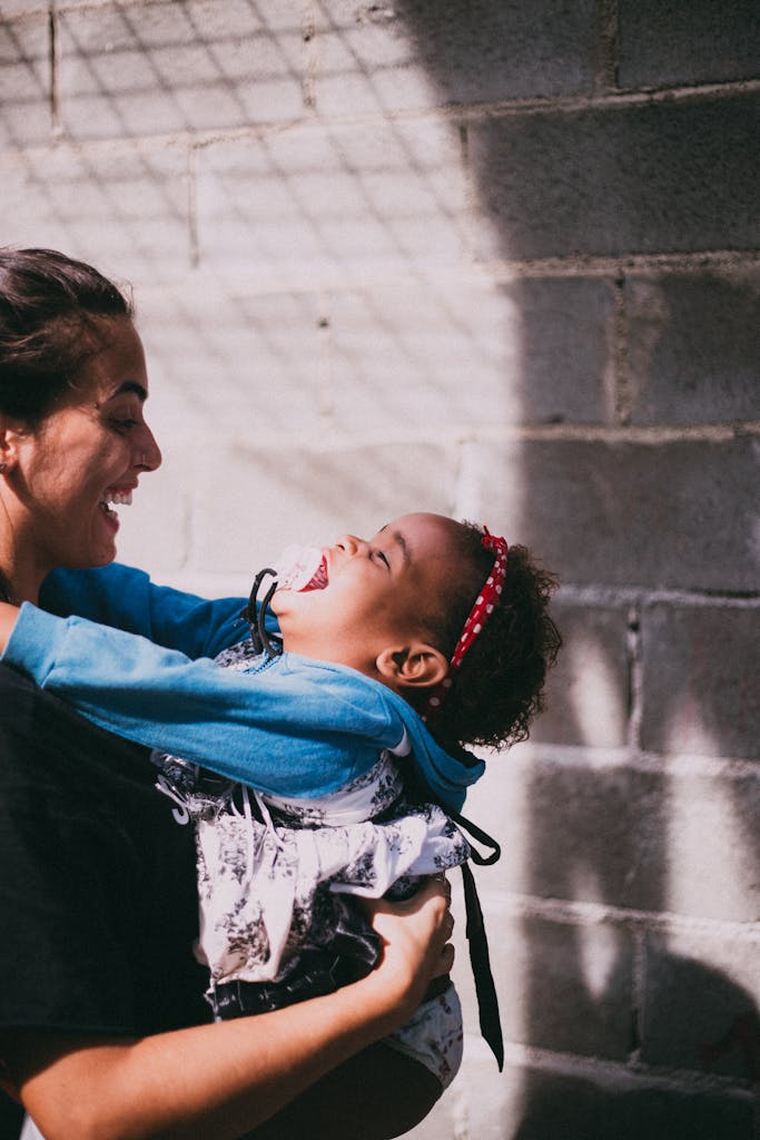 A mother and her child joyfully embrace, sharing a moment of happiness outdoors.